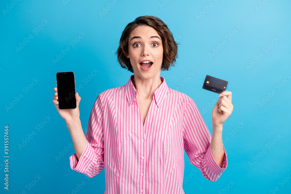 Photo of astonished lady hold smartphone credit card payment wear white pink formalwear shirt isolated on blue color background Photo of astonished lady hold smartphone credit card payment wear white pink formalwear shirt isolated on blue color background