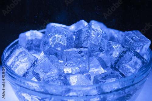 Bowl of wet ice close-up with water drops falling over