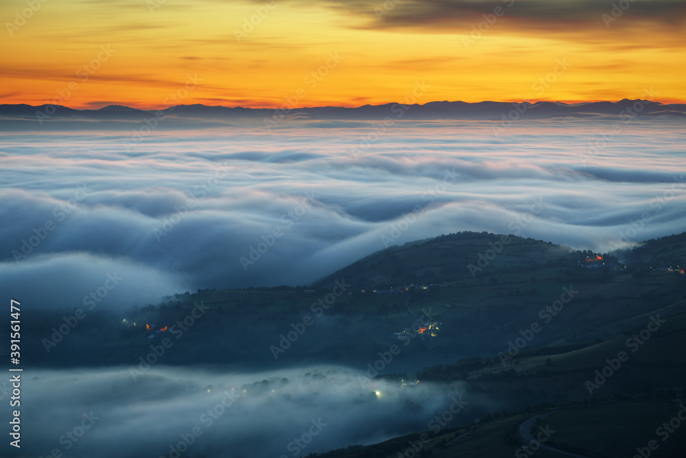 Blue waves of fog before sunrise between mountains and valleys