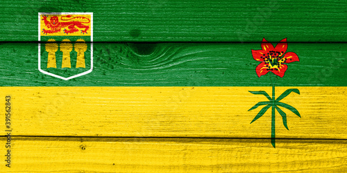 saskatchewan flag painted on old wood plank background. Brushed natural light knotted wooden board texture. Wooden texture background flag of saskatchewan