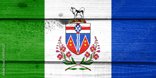 yukon flag painted on old wood plank background. Brushed natural light knotted wooden board texture. Wooden texture background flag of yukon