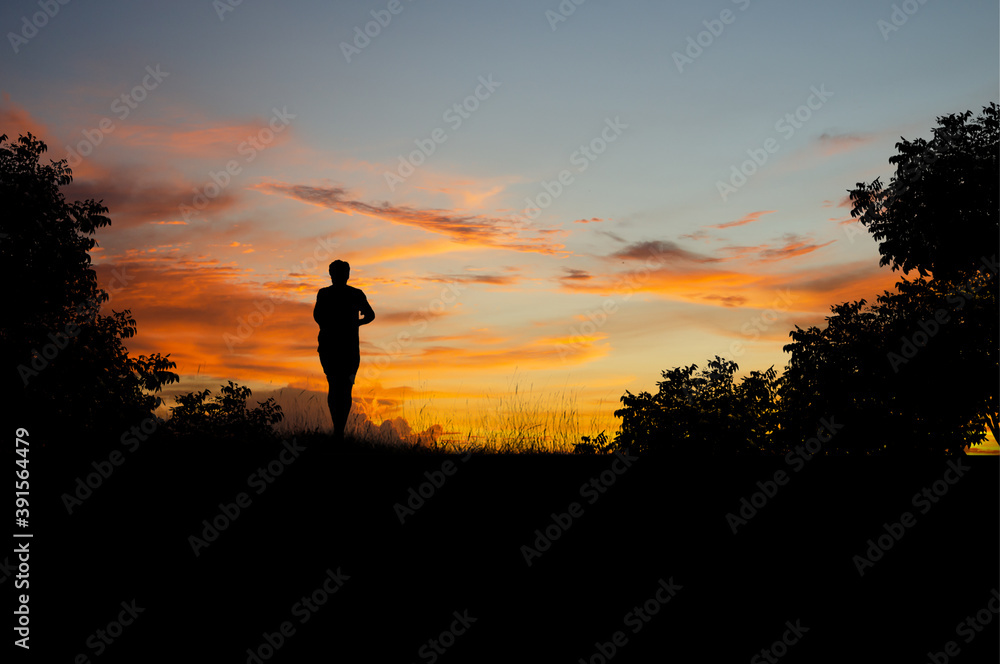 Silhouette of young fitness man  trail running in the forest on top of the mountain at morning with overcast sky. He likes to exercise by running in the morning, it makes him feel energized.