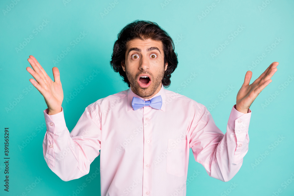 Photo of surprised wavy hair man dressed pink shirt two arms up open mouth isolated teal color background Photo of surprised wavy hair man dressed pink shirt two arms up open mouth isolated teal color background