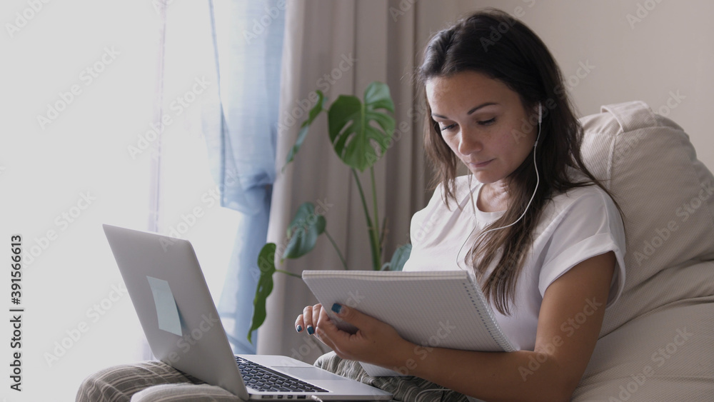 Young woman wears headset conference calling on laptop talks with online teacher studying, working from home. Lady student learning using computer webcam chat makes notes. Distance education concept Young woman wears headset conference calling on laptop talks with online teacher studying, working from home. Lady student learning using computer webcam chat makes notes. Distance education concept