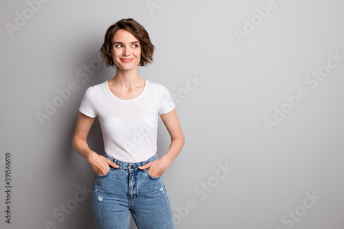 Photo of beautiful girl happy smile hands in pocket look empty space isolated over grey color background