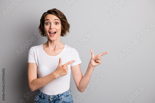 Photo of young excited amazed girl point fingers empty space ad offer sale promotion isolated over grey color background photo