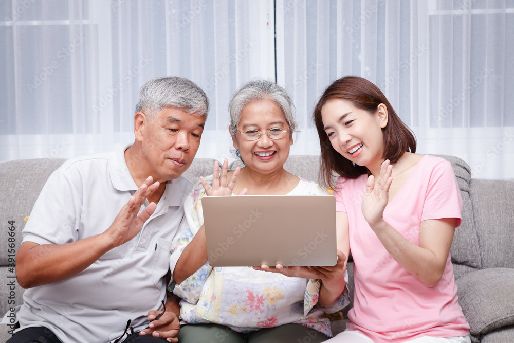 Asian family, parents and daughters online video calling greetings to grandchildren. Via laptop computer At the living room in the house During the coronavirus