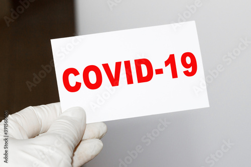 The doctor's hands show the word COVID-19 - . a gloved hand on a white background. Medical concept. the medicine