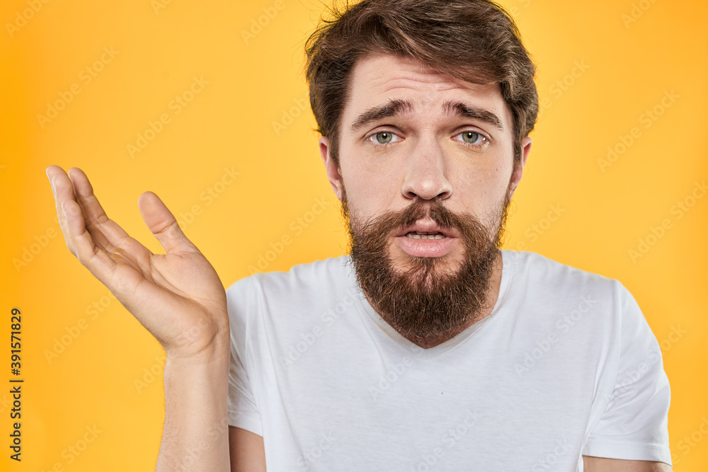 A man in a white t-shirt gestures with his hands studio lifestyle yellow background emotions A man in a white t-shirt gestures with his hands studio lifestyle yellow background emotions