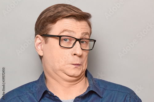 Portrait of funny confused surprised man with glasses