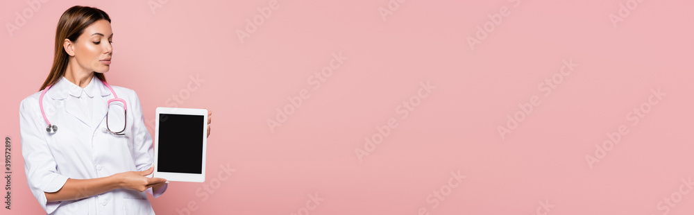 Doctor with stethoscope showing digital tablet with blank screen isolated on pink, banner