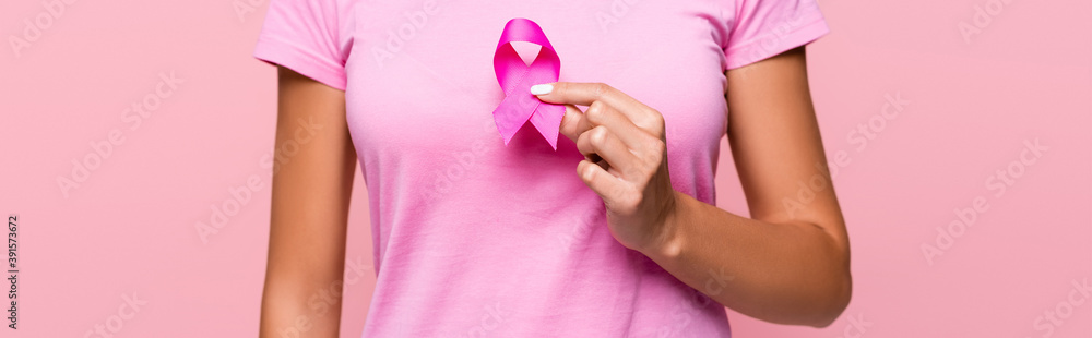 Cropped view of young woman holding breast cancer awareness sign isolated on pink, banner Cropped view of young woman holding breast cancer awareness sign isolated on pink, banner
