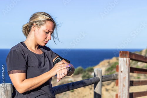 Blonde athlete woman looking at smartwatch