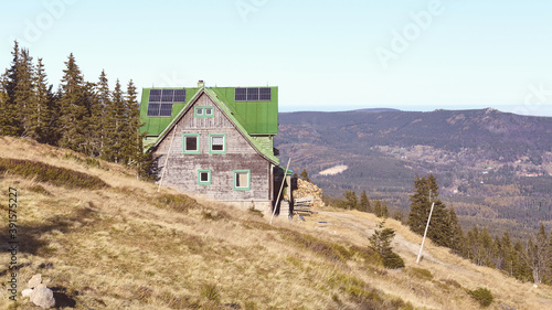 Retro toned picture of mountain hut with solar panels on roof.