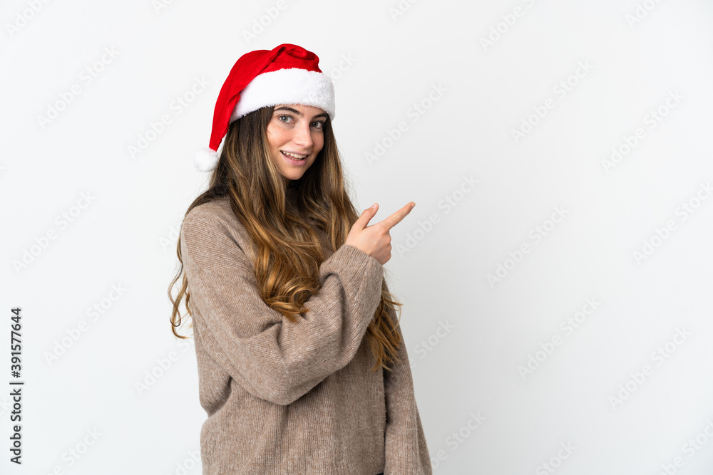 Caucasian girl with christmas hat isolated on white background pointing finger to the side