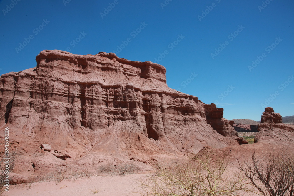 The red rocks of sandstone stand on desert area against blue sky background. The red rocks of sandstone stand on desert area against blue sky background.