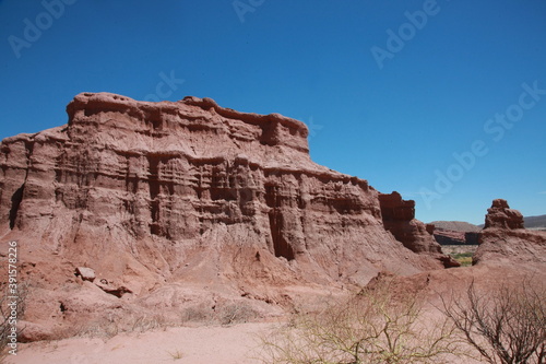 The red rocks of sandstone stand on desert area against blue sky background.