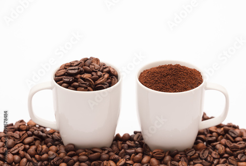 two white porcelain cup with coffee bean capsule and ground powder, coffee beans, with white background