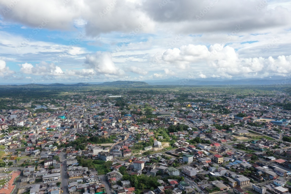 Aerial view over a large city with a beautiful cloudscape and in green covered hills in the background Aerial view over a large city with a beautiful cloudscape and in green covered hills in the background