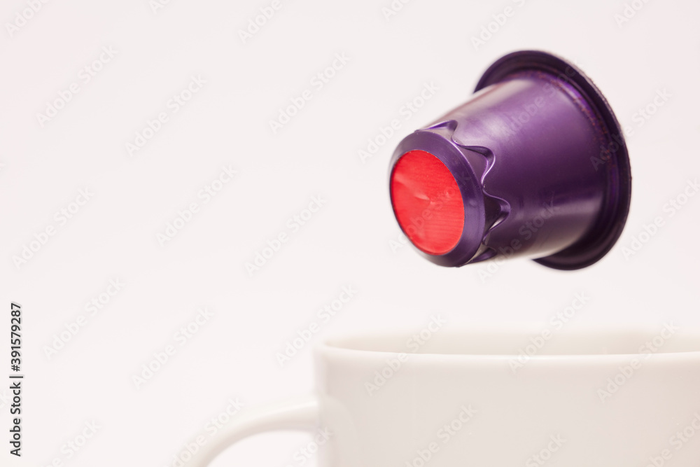purple and red capsule, flying over white porcelain cup, coffee powder and white background purple and red capsule, flying over white porcelain cup, coffee powder and white background