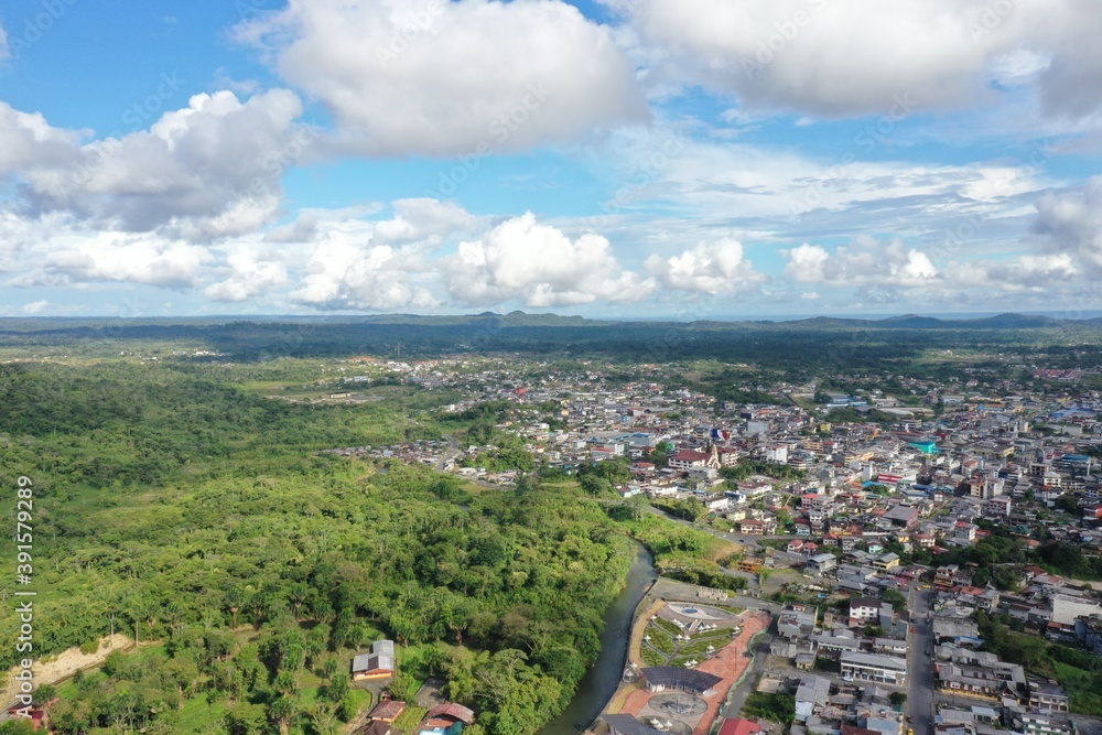 Obraz premium Aerial view of a small village located next to rainforest that starts at the edge of the city