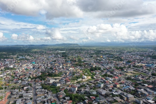 Aerial view over a large city with a beautiful cloudscape and in green covered hills in the background