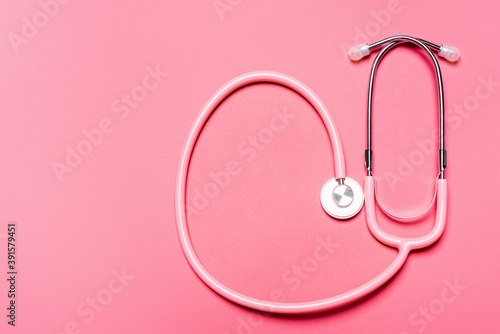 Top view of stethoscope on pink background, concept of breast cancer awareness