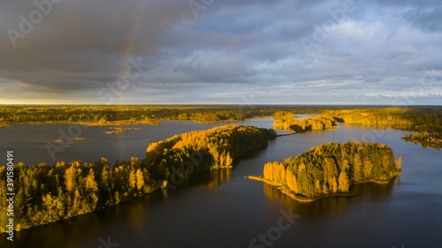 Autumn scenery with lake and islands and dark sky with rainbow photo