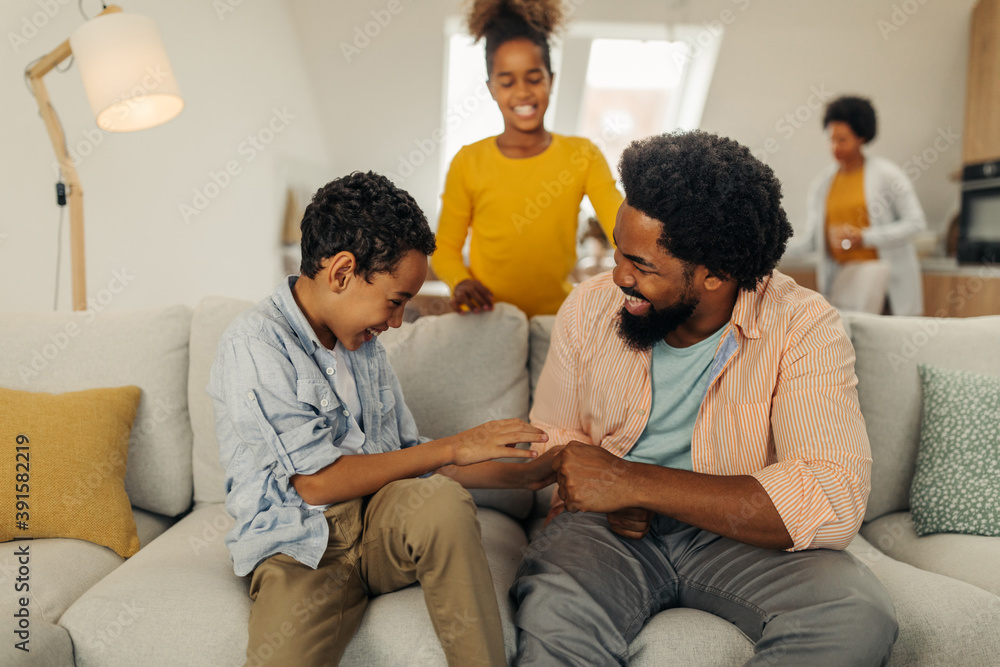 Afro family in the living room. Father tickling his children Afro family in the living room. Father tickling his children