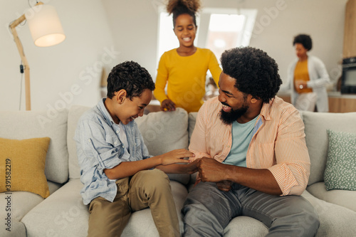 Afro family in the living room. Father tickling his children