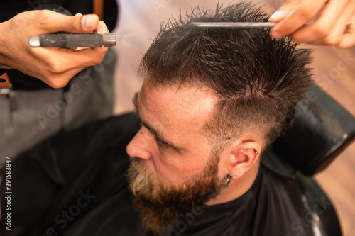 man with beard is combed in barbershop and sprayed with water dispenser