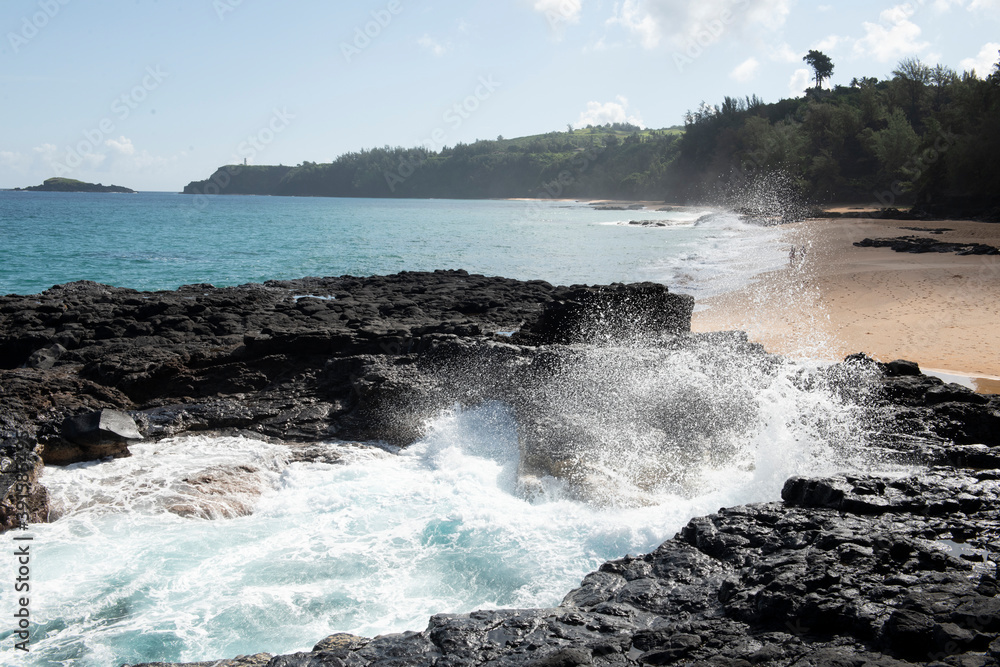 Waves crash into lava rock on empty Kauai beach