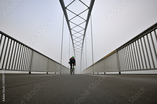 Ein Radfahrer auf einer Br  cke im Nebel