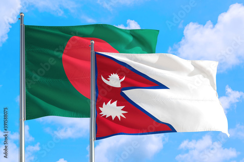 Nepal and Bangladesh national flag waving in the windy deep blue sky. Diplomacy and international relations concept.