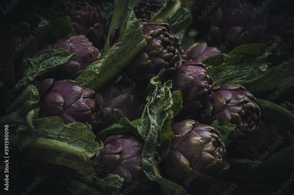 A pile of artichokes on a market stall. Close up photo with shallow focus.
