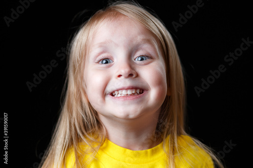 Close-up portrait of a cheerful little girl. Studio shot over dark background. Childhood concept.