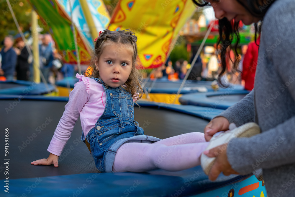 Mom puts on her daughter's sandals at the children's matinee on the trampoline. Mom puts on her daughter's sandals at the children's matinee on the trampoline.