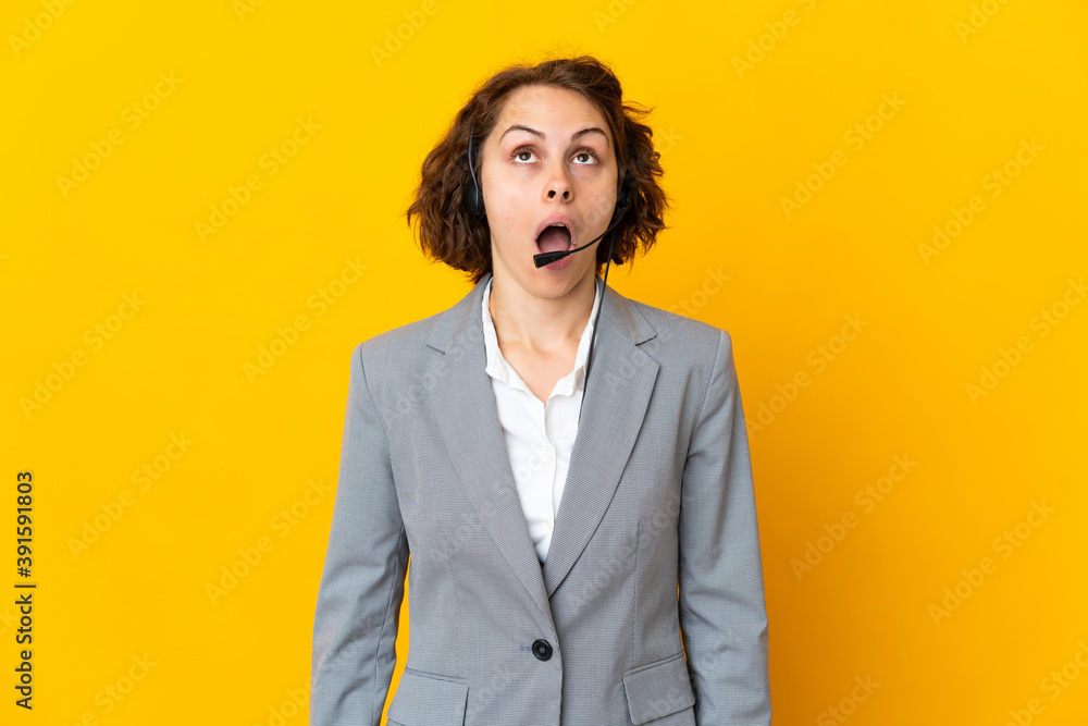 Young English woman isolated on yellow background looking up and with surprised expression Young English woman isolated on yellow background looking up and with surprised expression