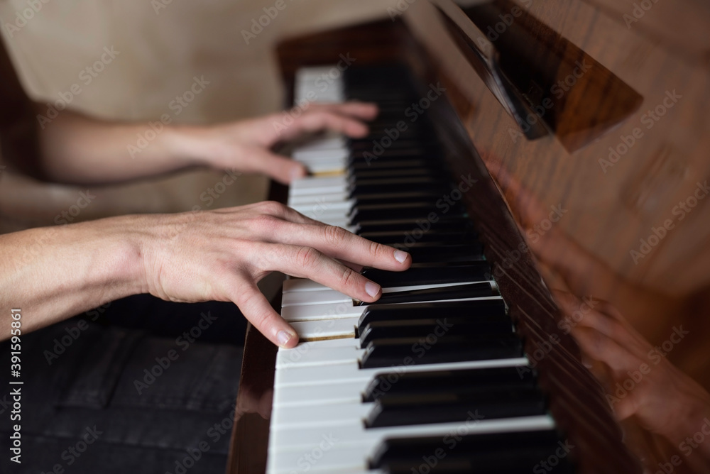 Fototapeta premium Hands of a boy on the keys of an old piano, the guy presses the keys and remembers his studies at the music school. Close up. Music learning concept