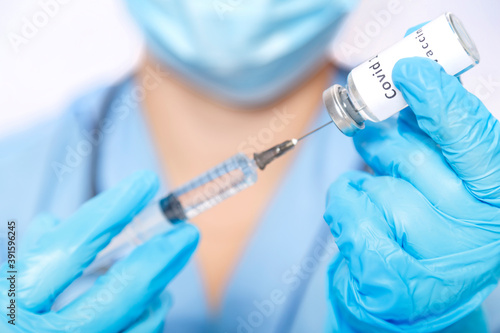 A gloved doctor fills a syringe with a virus vaccine.