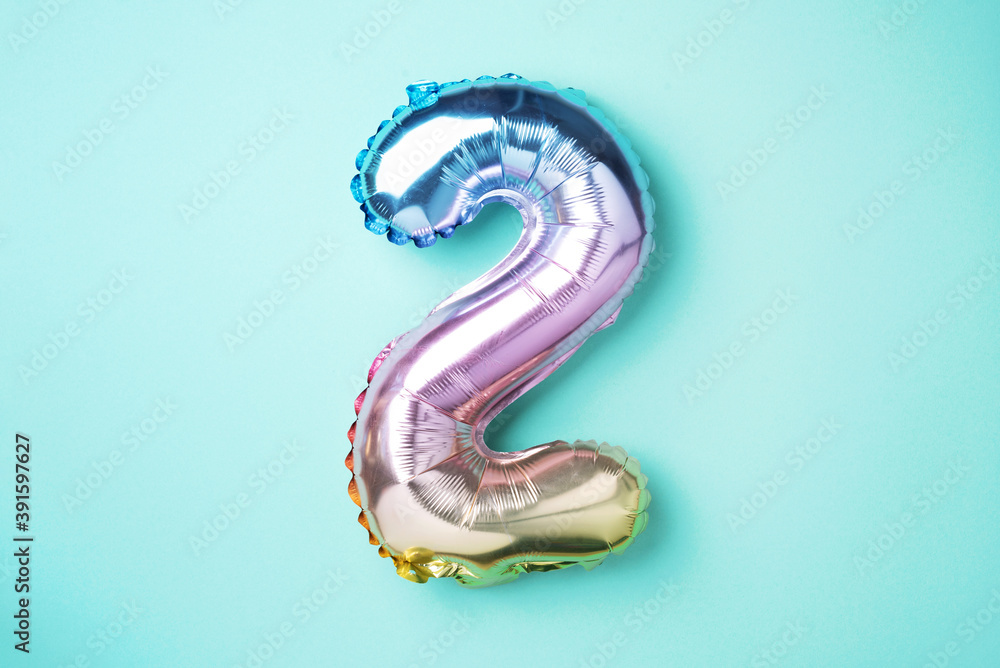 Creative layout. Rainbow foil balloon number and digit two 2. Birthday greeting card. Anniversary concept. Top view. Copy space. Stylish colored numeral over blue background. Numerical digit. Creative layout. Rainbow foil balloon number and digit two 2. Birthday greeting card. Anniversary concept. Top view. Copy space. Stylish colored numeral over blue background. Numerical digit.