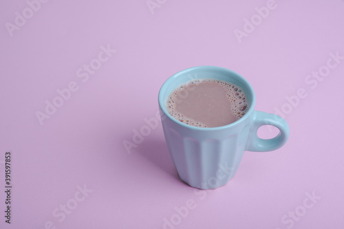 mug of blue color with cocoa on a pink background
