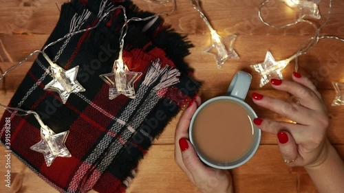a woman warms her hands on a mug of hot chocolate