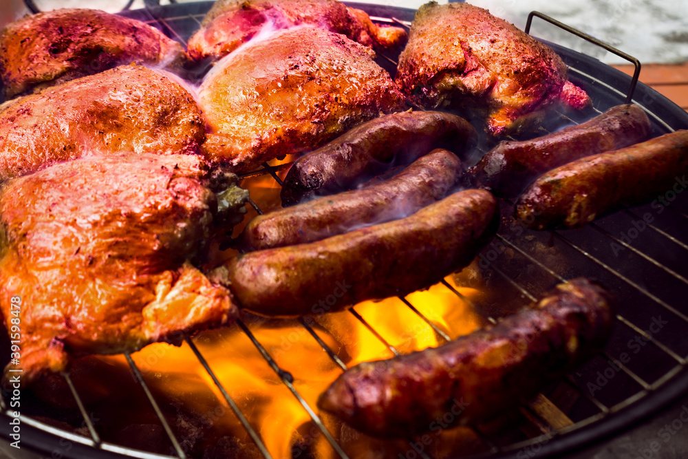 
barbecue with chicken and sausages on charcoal