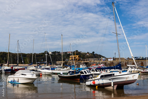Boats resting on the sand at lowtide in the picturesque harbour and seaside town of Tenby in Wales