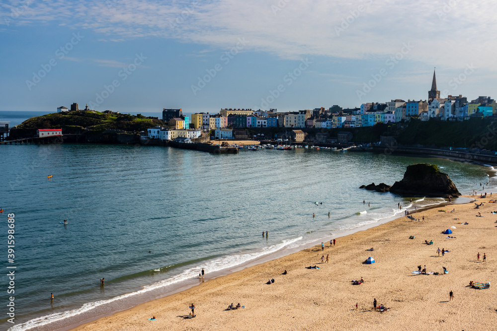 People enjoying late summer sunshine on a sandy beach in the picturesque seaside town of Tenby, Wales