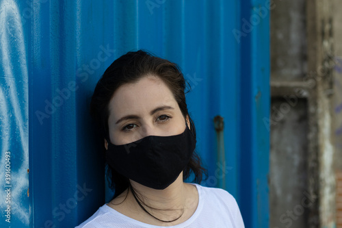 Mulher usando máscara para se proteger do covid19 encostada em um contêiner marítimo  photo