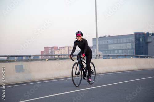 View of a girl exercising on a bicycle in the city in the morning at dawn. St. Petersburg Krestovsky Island Yakhtenny Bridge.