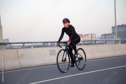 View of a girl exercising on a bicycle in the city in the morning at dawn. St. Petersburg Krestovsky Island Yakhtenny Bridge.