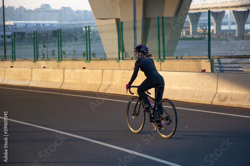 Evening workout of a woman on a bike. Play sports in the city. Yacht Bridge St. Petersburg.